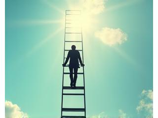 Person climbing a ladder against a clear sky, representing financial stability during a career transition.